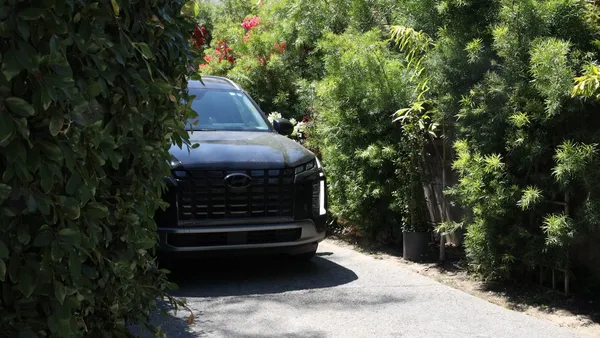 Black Hyundai Palisade SUV parked in a narrow California driveway lined with bougainvillea