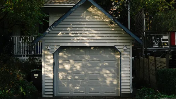 Garage door opening as a car arrives in a residential driveway