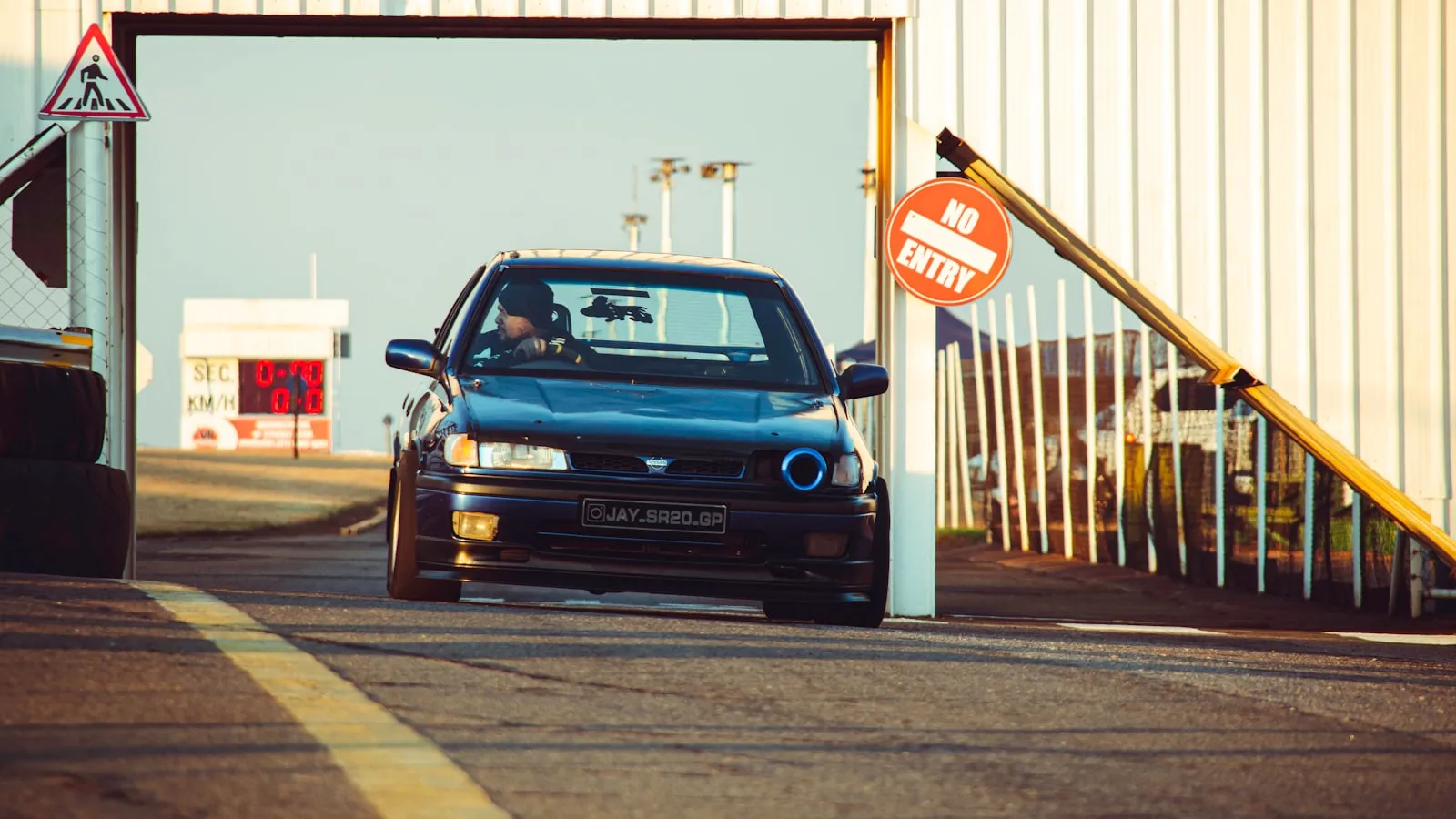 A car parked at a residential driveway gate entrance