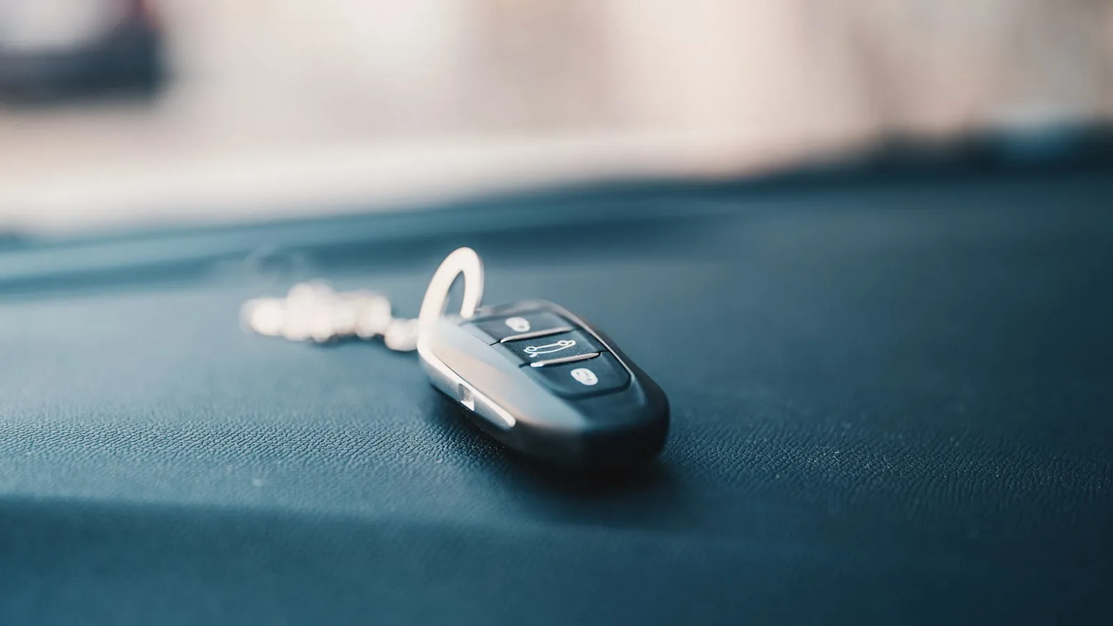 A small black plastic key fob with buttons resting on a dark surface, photographed close-up
