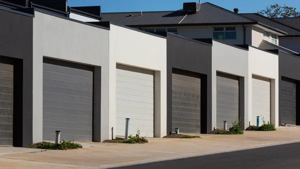 Row of modern townhouse garages with dark-gray and white doors along a shared driveway