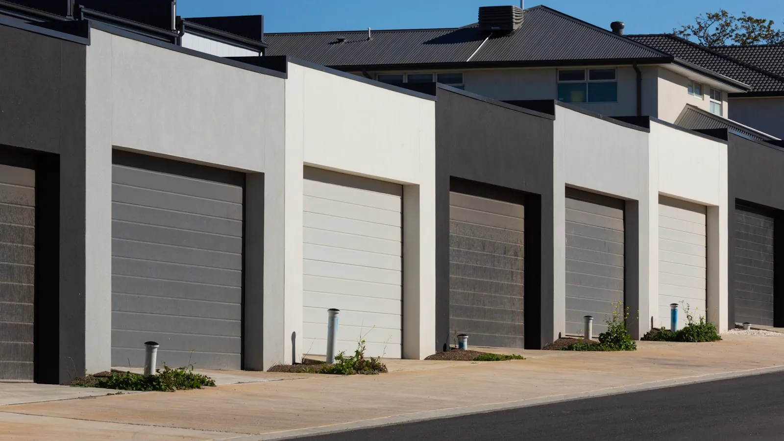Row of modern townhouse garages with dark-gray and white doors along a shared driveway