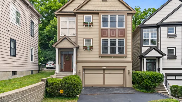 Tan suburban house with two-car garage and landscaped front yard