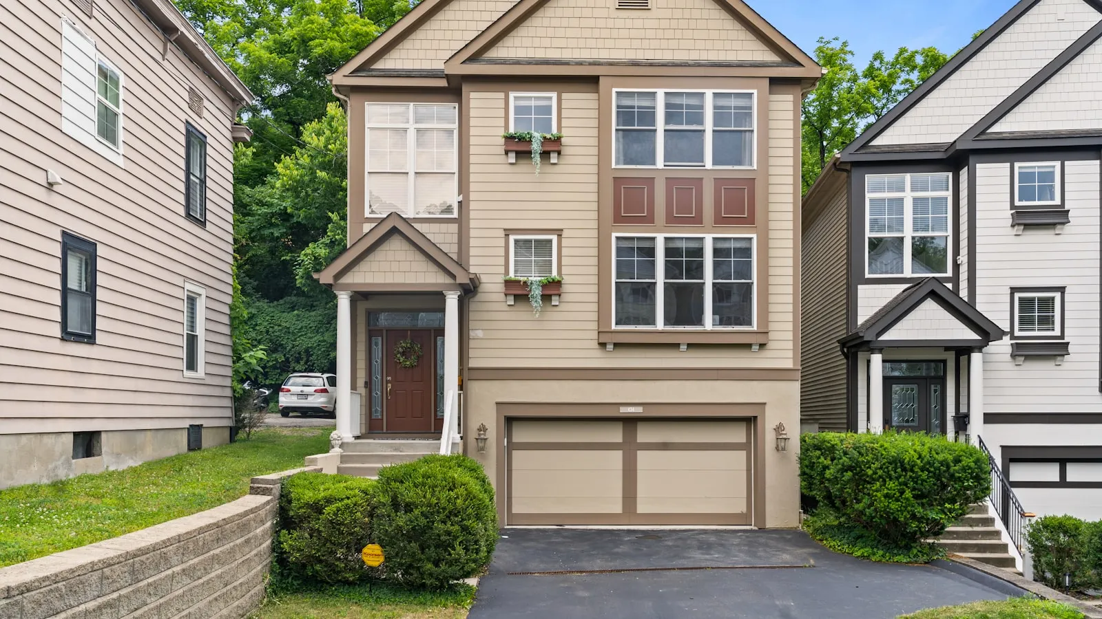 Tan suburban house with two-car garage and landscaped front yard
