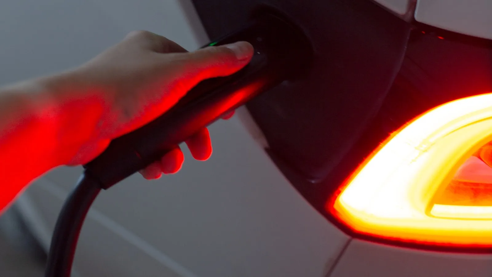 Electric vehicle charge port with green charge indicator light, parked in a home garage