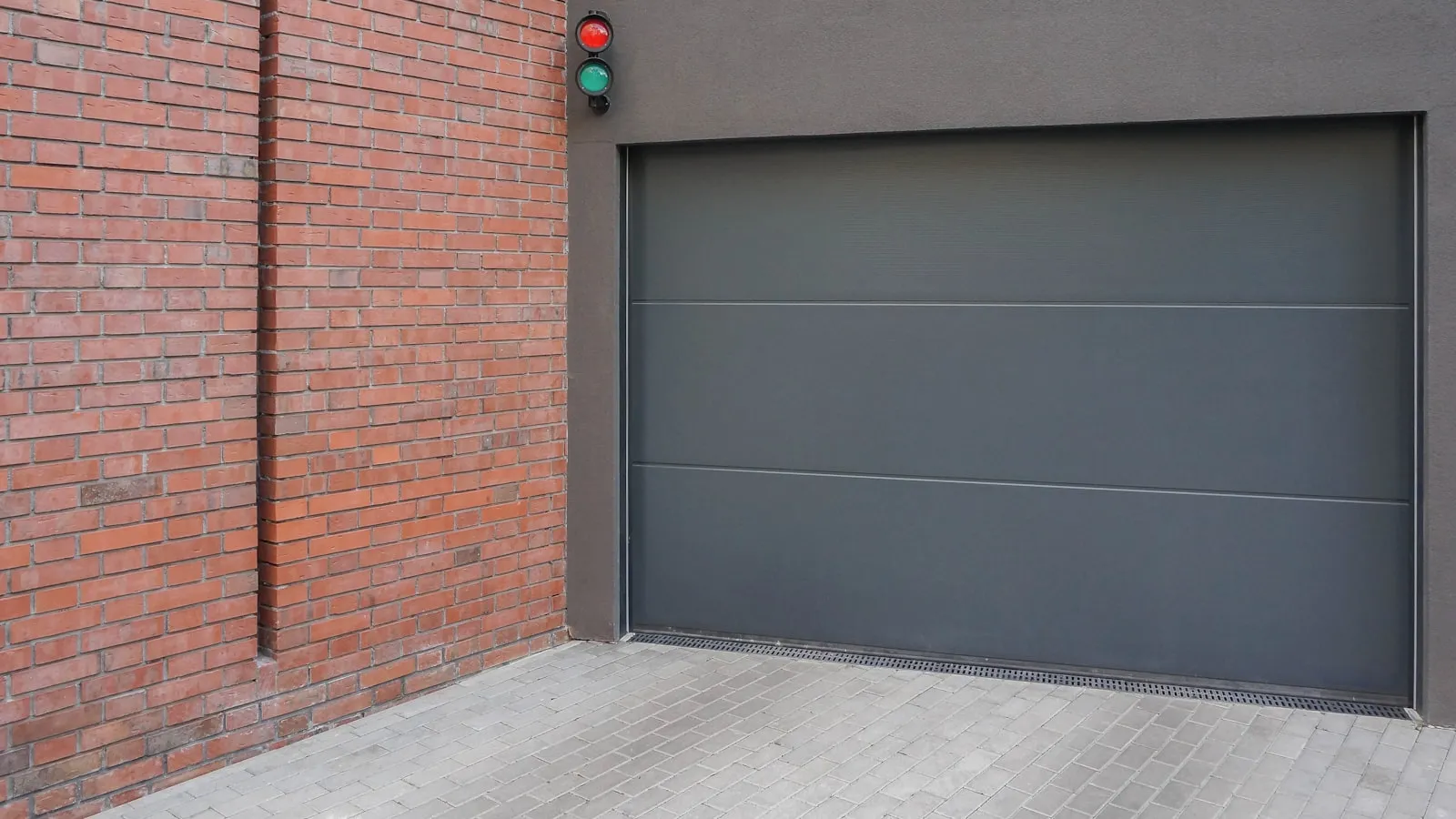 Grey garage door next to a brick wall on a residential building