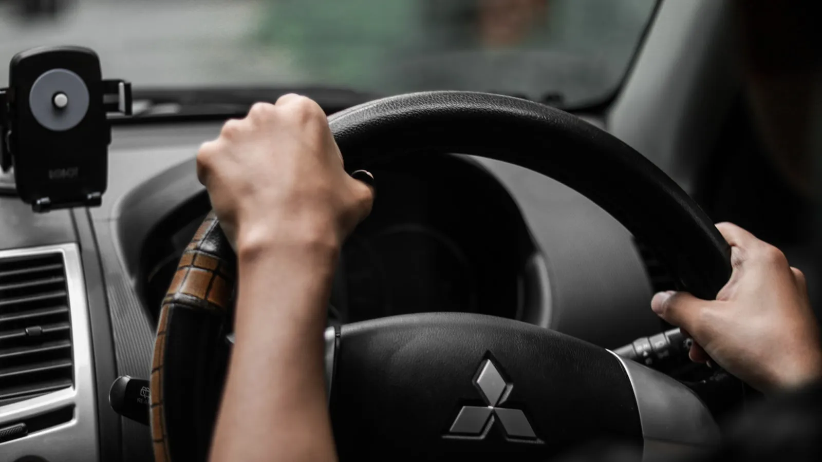Driver's point-of-view looking out through a car windshield from behind the steering wheel