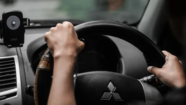 Driver's point-of-view looking out through a car windshield from behind the steering wheel