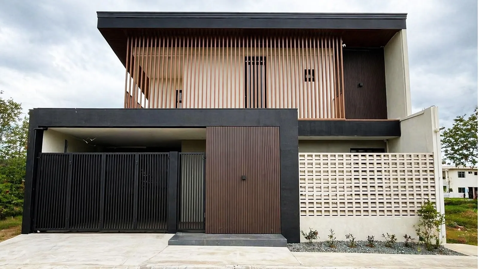 A dark metal slat sliding gate at the entrance of a contemporary house