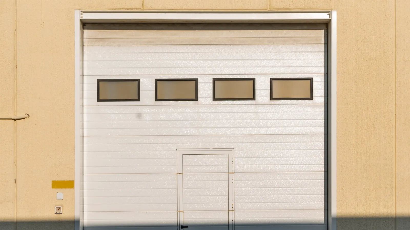 Garage door with a small window panel, viewed from outside on a residential street