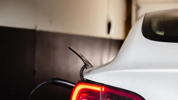 White Tesla Model 3 parked inside a home garage, rear tail-light and charge port visible