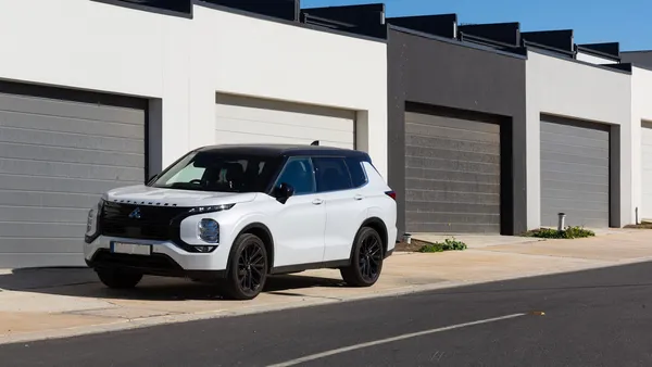 A white SUV parked at the curb in front of a row of modern gray garage doors