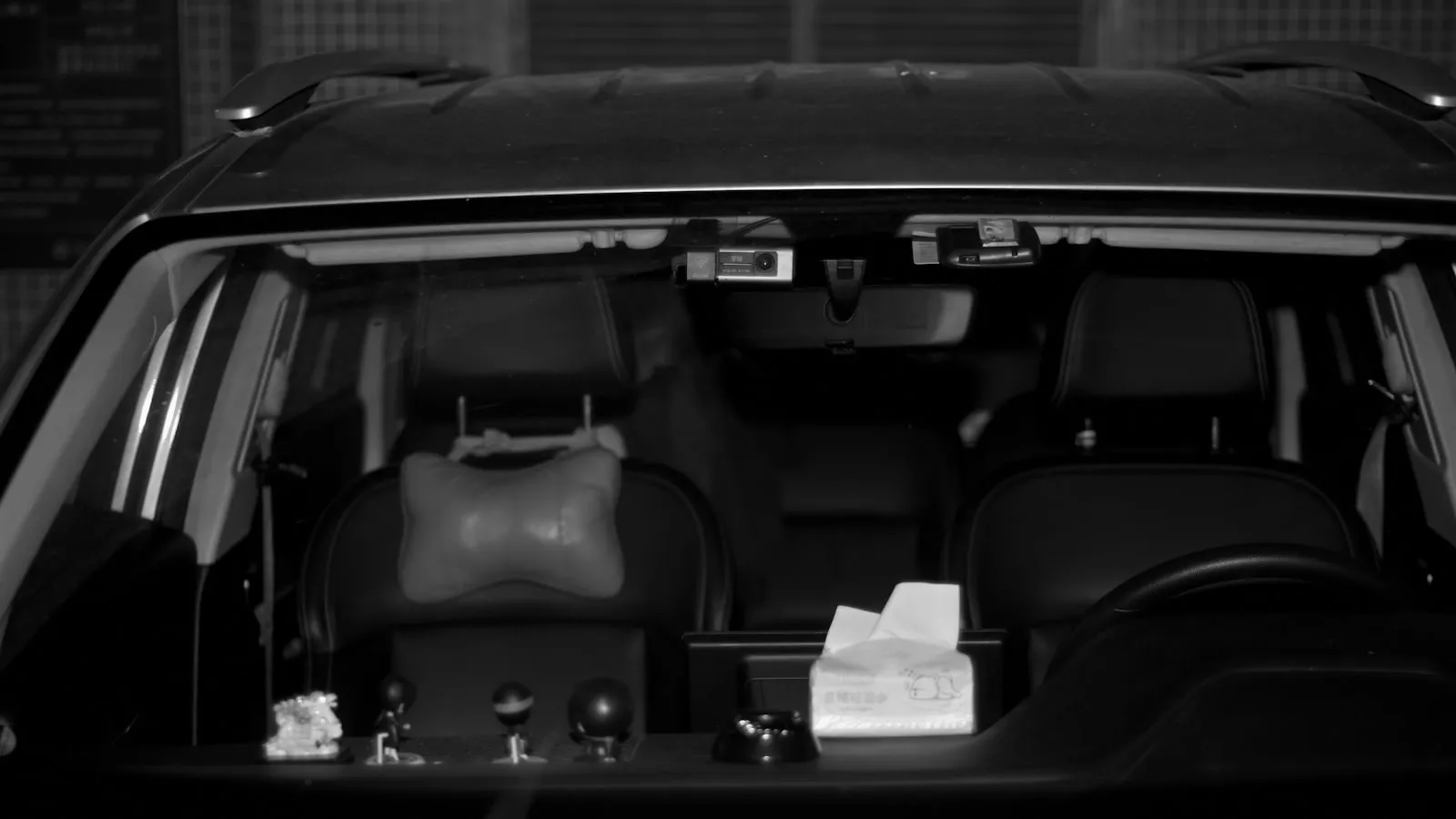 View through a car windshield showing the dashboard and rearview mirror area with the visor folded down